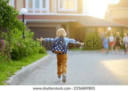 Little schoolboy joyfully running to school after holiday. Child meeting with friends. Education for children. Back to school concept. Kids friendship.