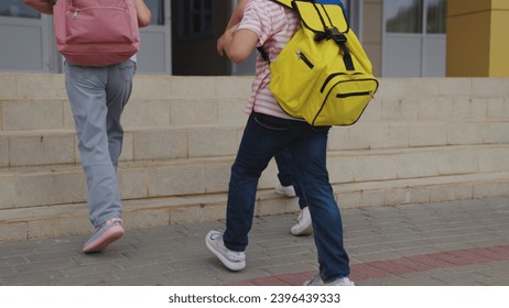 Little schoolchildren with schoolbags go upstairs to school entrance closeup. Little children group with backpacks walks to school building. Children class go up steps together to school - Powered by Shutterstock