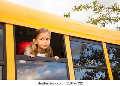 Little Schoolgirl Looking Through A Schoolbus Window