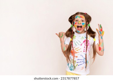 A little schoolgirl with painted hands and face with multicolored paints. A girl stained with paints. The concept of children's creativity. Funny child draws with his hands. Copy space. Banner. - Powered by Shutterstock