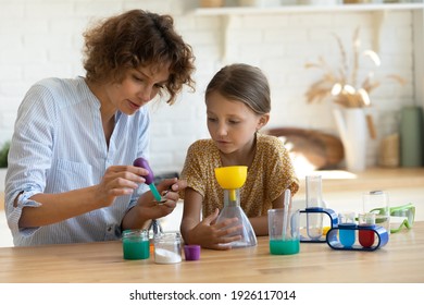 Little scientist. Curious school age daughter play with mom engaged at education activity make funny experiment. Interested small girl watch elder sister doing chemical test use chemistry set for kids - Powered by Shutterstock