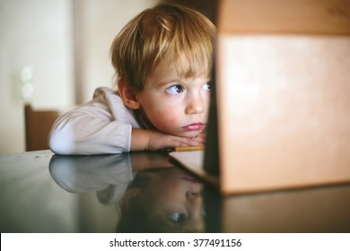 Little Serious And Lonely Child Girl Sitting And Looking On Tablet Laptop