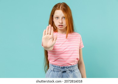 Little serious strict redhead kid girl 12-13 years old wear pink striped t-shirt do stop palm gesture say no refusing isolated on pastel blue background studio. Children lifestyle childhood concept - Shutterstock ID 2072816018