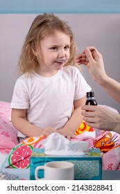 A Little Sick Girl Drinks Medicine With A Spoon
