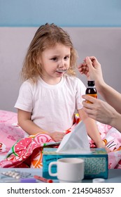 A Little Sick Girl Drinks Medicine With A Spoon