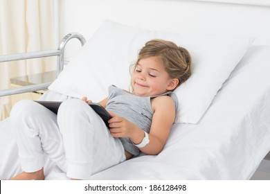 Little sick girl using digital tablet while lying in hospital bed - Powered by Shutterstock