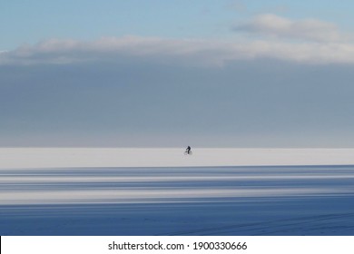 Little silhouette of riding biker on horizon on frozen Baltic Sea in Pucka Bay on winter day - Shutterstock ID 1900330666