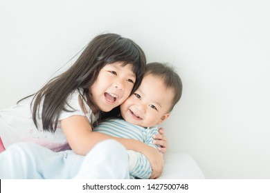 Little sister hugging her baby brother in the morning.Toddler kid meeting new sibling.Cute girl and baby boy relax at home in Japan.Family with children at home. Social distancing covid-19 coronavirus