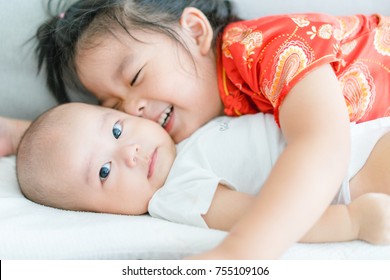 Little Sister Hugging Her Baby Boy Brother.Toddler Kid Meeting New Sibling. Cute Girl And New Baby Boy Relax In A Sofa Bed. Family With Children At Home. Love, Trust And Tenderness