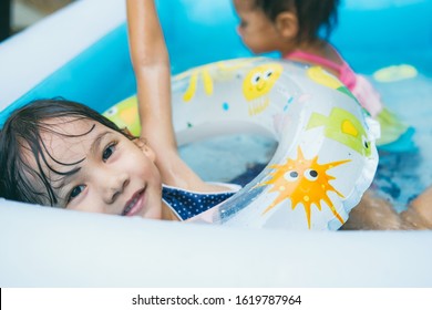 Little Sisters Playing In The Inflatable Pool Inside The House.