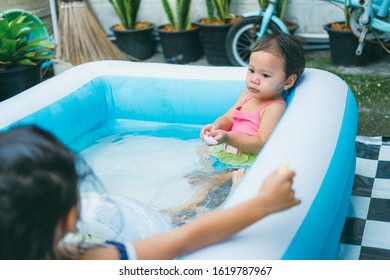 Little Sisters Playing In The Inflatable Pool Inside The House.