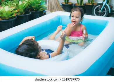 Little Sisters Playing In The Inflatable Pool Inside The House.