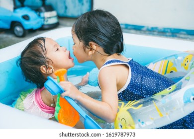 Little Sisters Playing In The Inflatable Pool Inside The House.