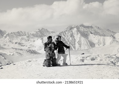 Little Skier And Her Father With Tablet Device On Top Of Snowy Ski Slope At Sun Winter Day. Caucasus Mountains, Georgia, Region Gudauri. Black And White Retro Toned Image.

