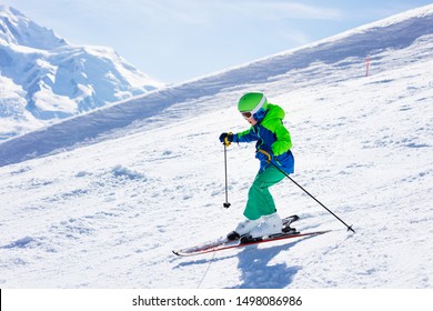Little skier riding downhill in high mountains