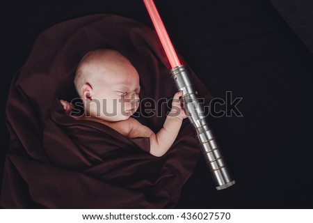 Little Sleeping Cute Newborn Baby with Laser Beam In Brown Mantle Cape. Isolated On Black Background