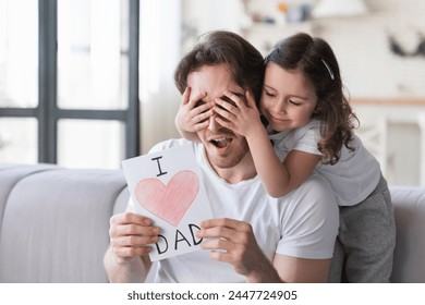 Little small daughter kid making surprise present for her father for father`s day, giving him a postcard with heart. I love you, dad! Family holiday, spending time together, congratulations - Powered by Shutterstock