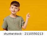 Little small happy boy 6-7 years old in green casual t-shirt point index finger aside on workspace area isolated on plain yellow background studio portrait. Mother
