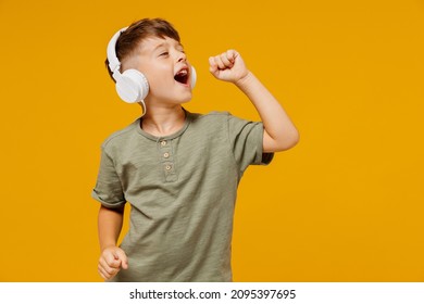 Little small happy boy 6-7 years old wearing green t-shirt headphones listen to music sing song in microphone isolated on plain yellow background studio. Mother's Day love family lifestyle concept. - Shutterstock ID 2095397695