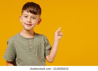 Little small happy boy 6-7 years old in green casual t-shirt point index finger aside on workspace area isolated on plain yellow background studio portrait. Mother's Day love family lifestyle concept. - Shutterstock ID 2110550213