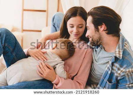 Little small kid child son daughter toddler sleeping on mother`s hands while loving father relaxing spending time with family. Happy moments time together at home. Parenthood