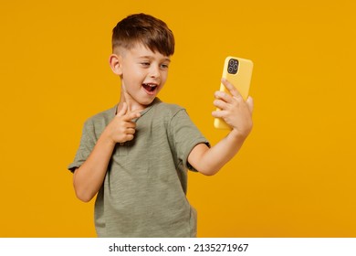 Little Small Smiling Boy 6-7 Years Old In Green T-shirt Doing Selfie Shot On Mobile Cell Phone Point Finger On Camera Isolated On Plain Yellow Background. Mother's Day Love Family Lifestyle Concept