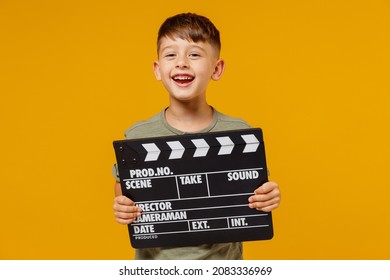 Little small smiling happy boy 6-7 years old wearing green t-shirt holding classic black film making clapperboard isolated on plain yellow background studio Mother's Day love family lifestyle concept