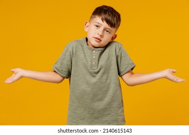 Little Small Uncertain Doubtful Caucasian Boy 6-7 Years Old Wearing Green Casual T-shirt Spreading Hands Isolated On Plain Yellow Background Studio Portrait. Mother's Day Love Family Lifestyle Concept