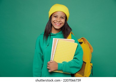 Little smart satisfied fun kid teen girl of African American ethnicity 13-14 years old wear casual hoody hat backpack hold notebooks isolated on plain dark green background Childhood education concept - Shutterstock ID 2207066739