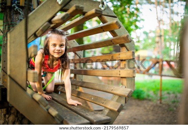 Little smiling adorable girl passing trail in sky\
rope park in summer