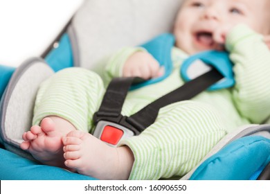 Little smiling baby child fastened with security belt in safety car seat
