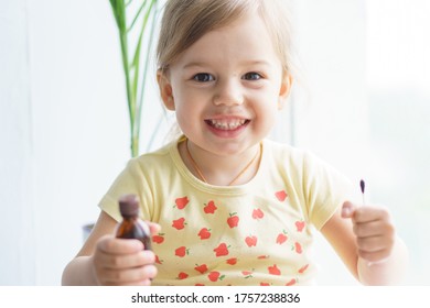 Little Smiling Girl Holding A Medicine Jar Of Iodine And An Ear Stick In Her Hands. Treatment Of Rashes, Acne, Pimples Dermatic Diseases, Contagious Mollusks On Skin In Children. Copy Space.