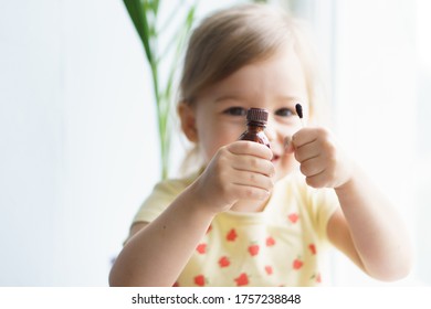 Little Smiling Girl Holding A Medicine Jar Of Iodine And An Ear Stick In Her Hands. Treatment Of Rashes, Acne, Pimples Dermatic Diseases, Contagious Mollusks On Skin In Children. Copy Space.Soft Focus