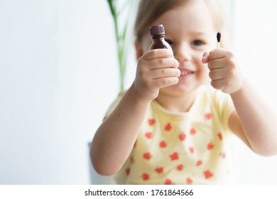 Little Smiling Girl Holding A Medicine Jar Of Iodine And An Ear Stick In Her Hands. Treatment Of Rashes, Acne, Pimples Dermatic Diseases, Contagious Mollusks On Skin In Children. Copy Space.Soft Focus