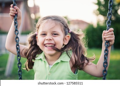 Little Smiling Girl Swinging Close Up Portrait.