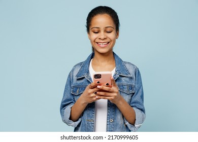 Little Smiling Happy Kid Teen Girl Of African American Ethnicity 12-13 Years Old In Denim Jacket Hold In Hand Use Mobile Cell Phone Isolated On Pastel Plain Light Blue Background. Childhood Concept