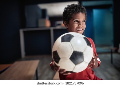 A little soccer player posing with the ball in a locker room - Powered by Shutterstock