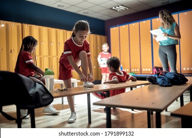 A little soccer player putting on sneakers in a locker room - Powered by Shutterstock