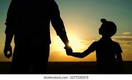 Little son, dad hold hands close up in nature in sun. Child father walk in park at sunset, family trust concept. Parent, kid boy outing together. Adoption of child. Happy family, teamwork. Silhouette - Powered by Shutterstock