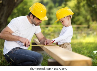 Little son helping his father with building work