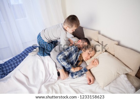 Similar – Mother reading book to her sons in the bed