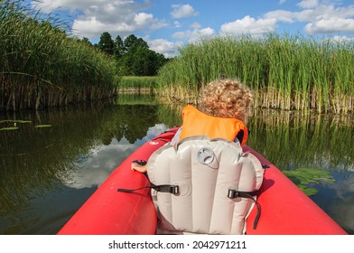 A Little Sporty Girl In A Life Jacket Floats On The Zdwyzh River On A Red Kayak With A Black Dog Cocker Spaniel. Ukraine