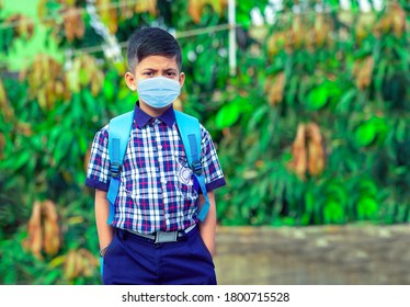 Little Student Boy Wearing School Uniform And Face Mask Going To School With Bag Pack In Corona Virus Pandemic.