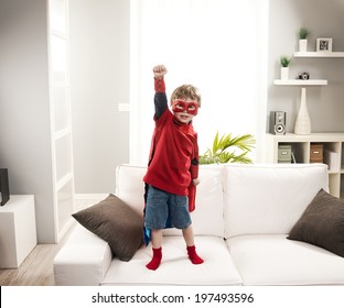 Little superhero boy standing on sofa and posing like a real hero. - Powered by Shutterstock