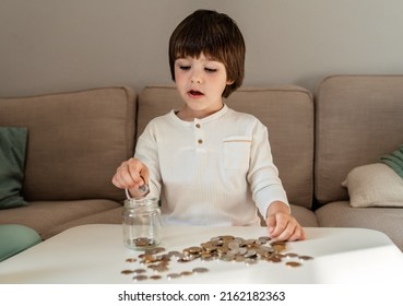 Little Toddler Boy Counting Money Putting Coins Into Glass Jar. Kid Calculating Saving From Change Learning Financial Literacy.