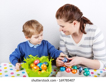 Little Toddler Boy And His Mother Having Fun With Easter Egg Hunt, Traditional Action In Germany For Eastern Holiday