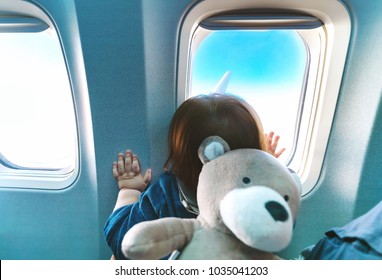 Little toddler boy looking out an airplane window while flying