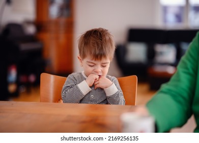 Little Toddler Boy Sitting At Wooden Table Sadly Looking Sideways