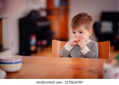 Little Toddler Boy Sitting At Wooden Table Sadly Looking Sideways