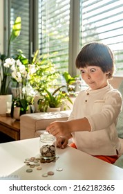 Little Toddler Boy With Surprised Face Counting Money Putting Coins Into Glass Jar. Kid Calculating Saving From Change Learning Financial Literacy.